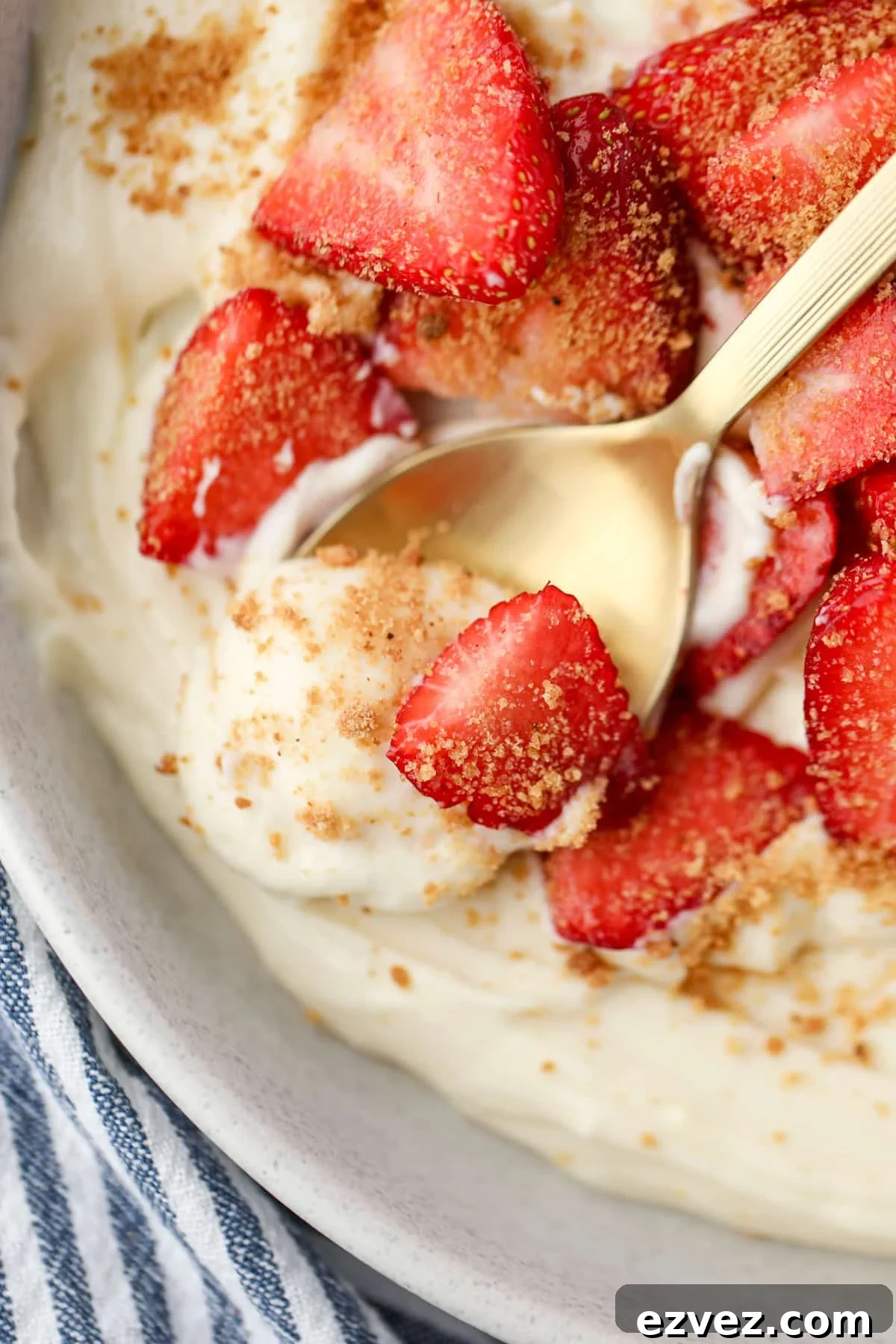 A close up of a spoon scooping yogurt from a bowl with fresh strawberries.