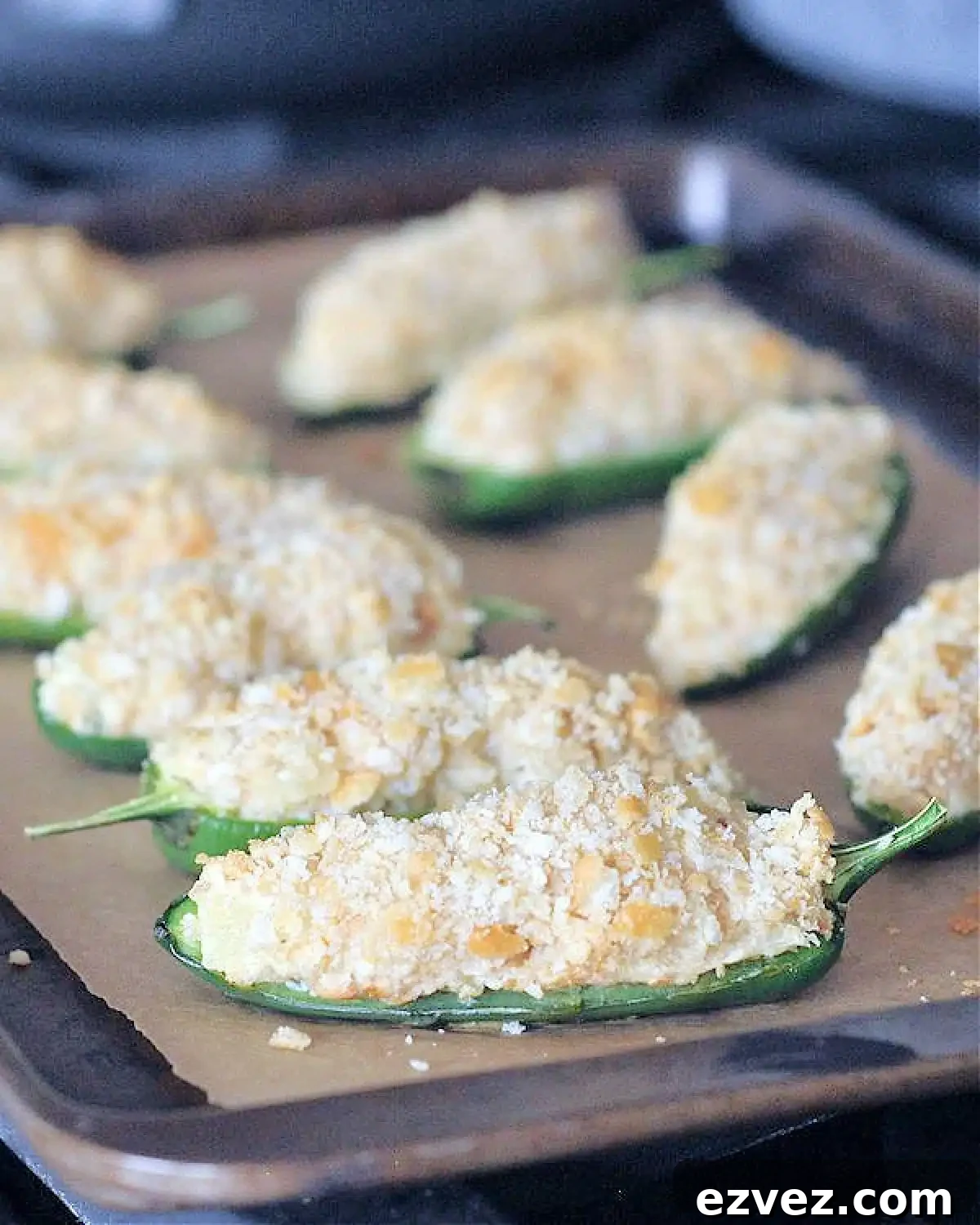 Pineapple jalapeño poppers with cracker breading on a baking sheet.