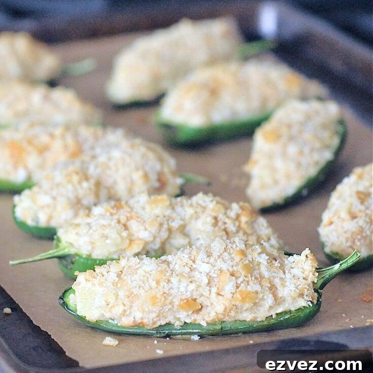 Pineapple jalapeño poppers with cracker breading on a baking sheet.