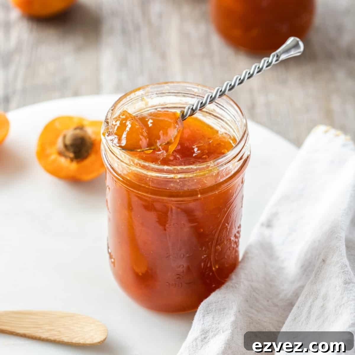 Shot of open jar of jam, with a silver spoon sitting on top.