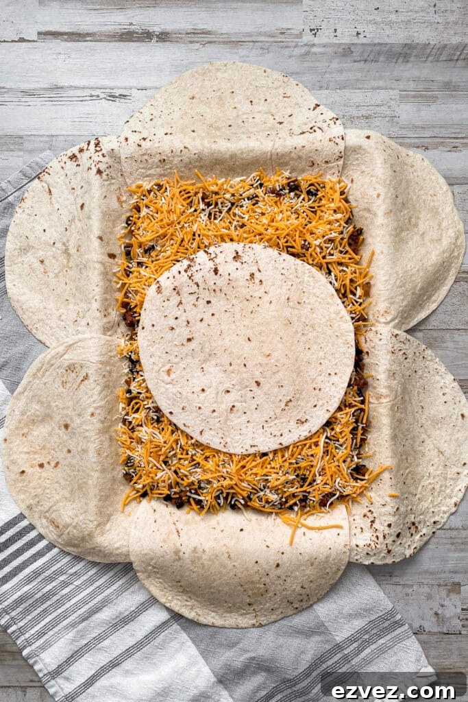 sheet pan quesadillas lined with tortillas, meat mixture, cheese