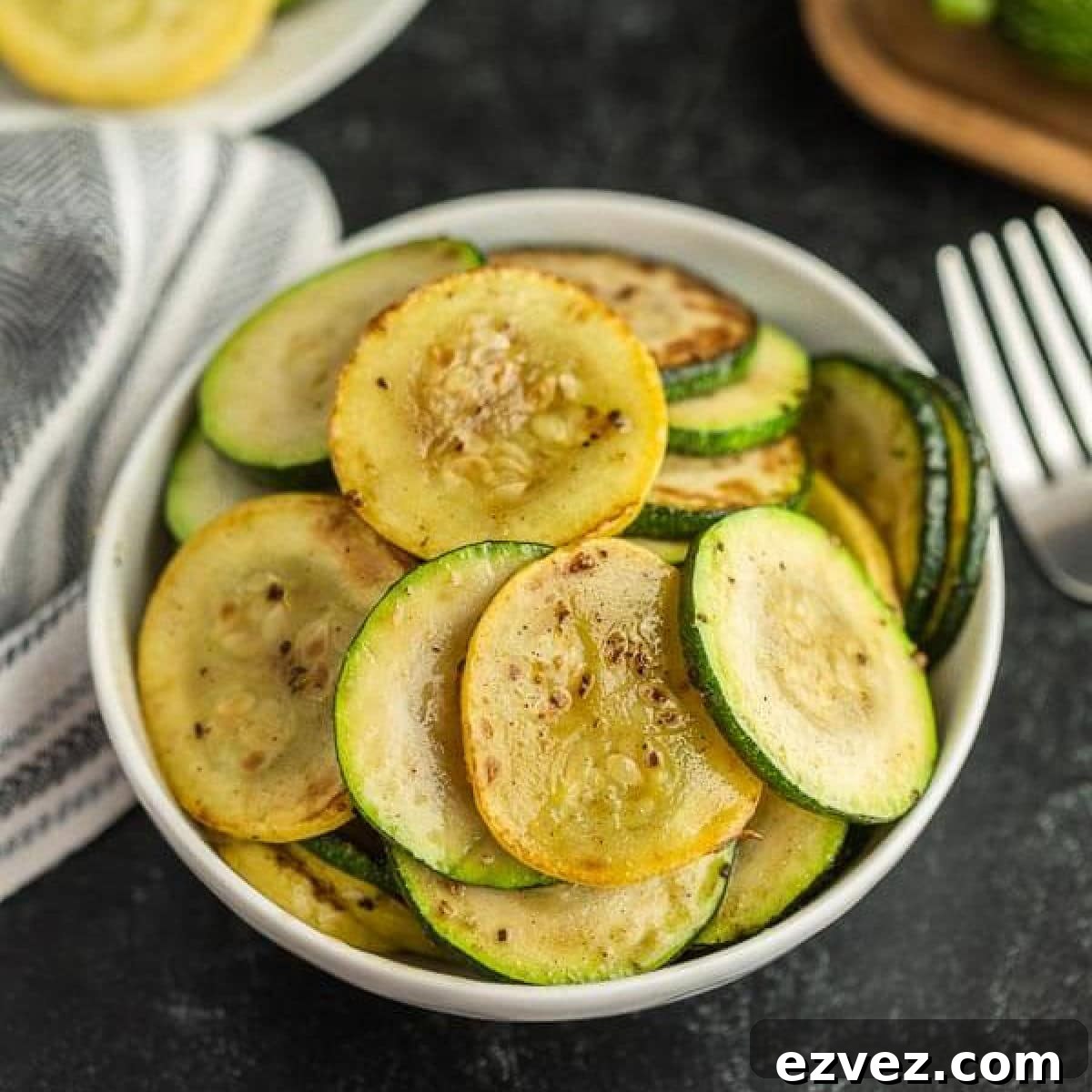 A white bowl filled with sautéed slices of Blackstone Zucchini and Squash, seasoned with pepper.