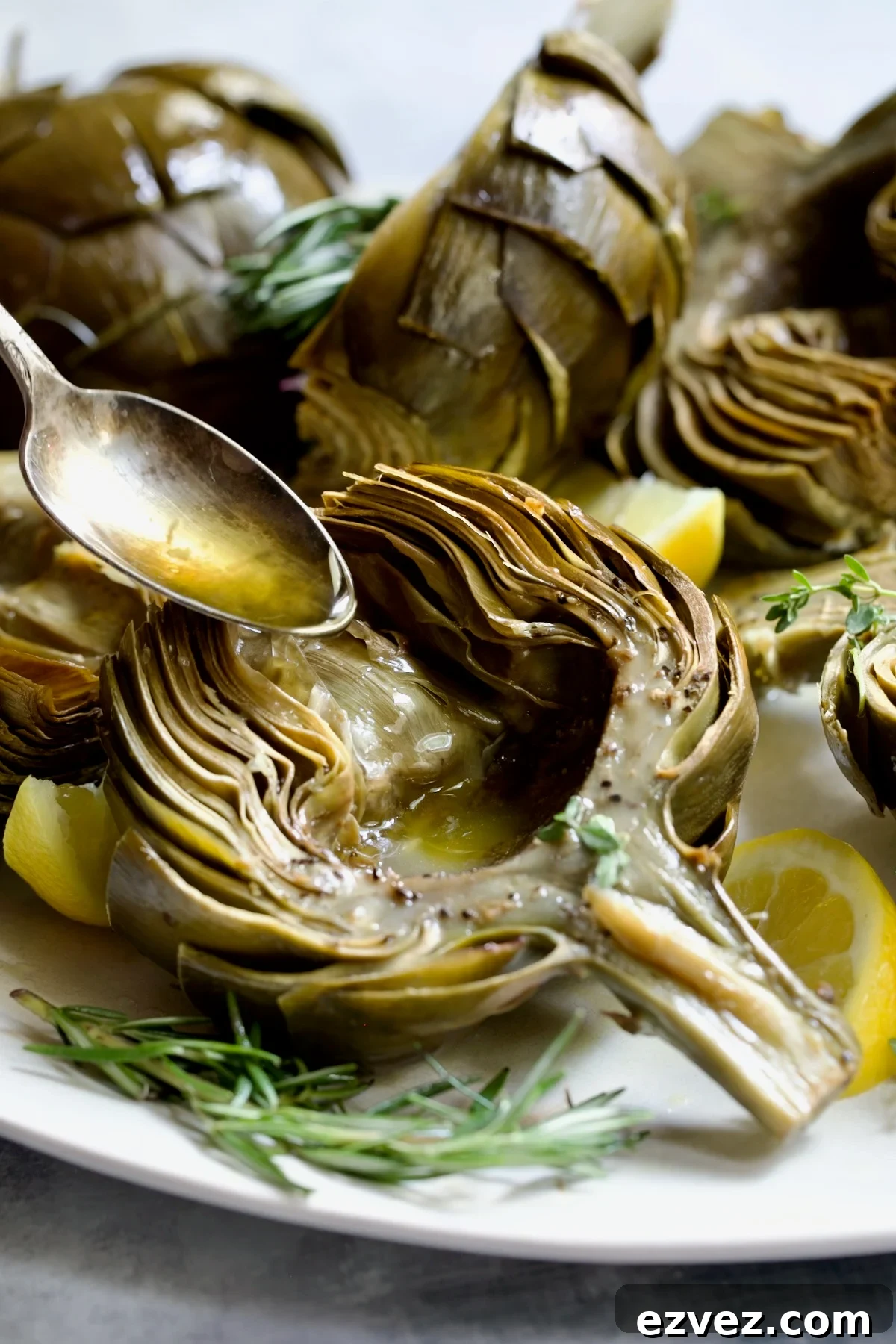 Butter being poured into the well of a roasted artichoke half.