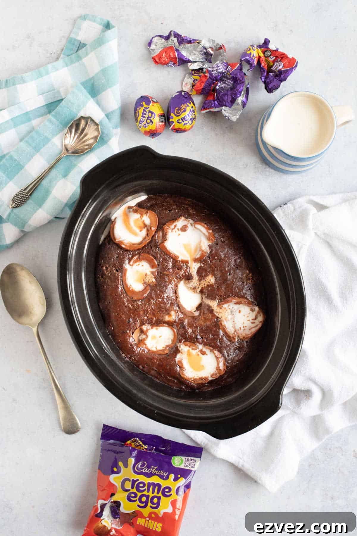 Slow cooker chocolate pudding in a slow cooker basin, with creme egg wrappers around the outside.