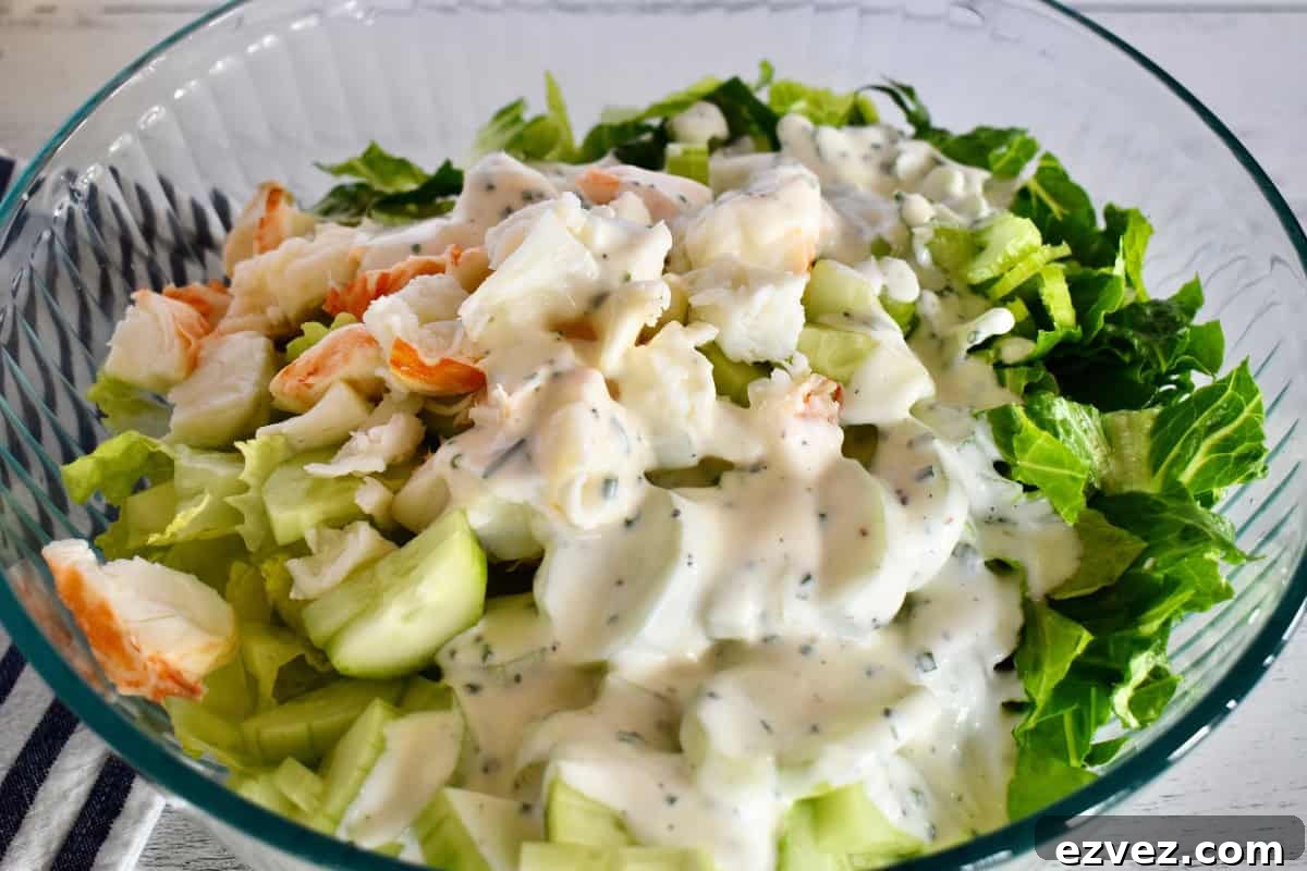 Creamy buttermilk dressing poured on top of the ingredients in a white dish. 