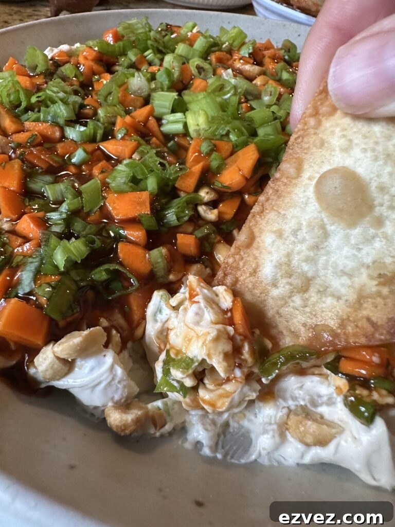 A close up of a won ton chip being dipped into egg roll dip