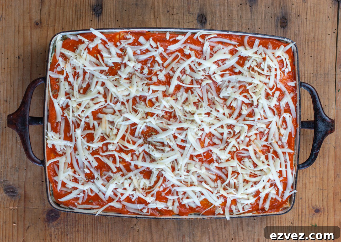 Add the final layer of veggie mixture and tortillas, top with sauce and grated cheese
