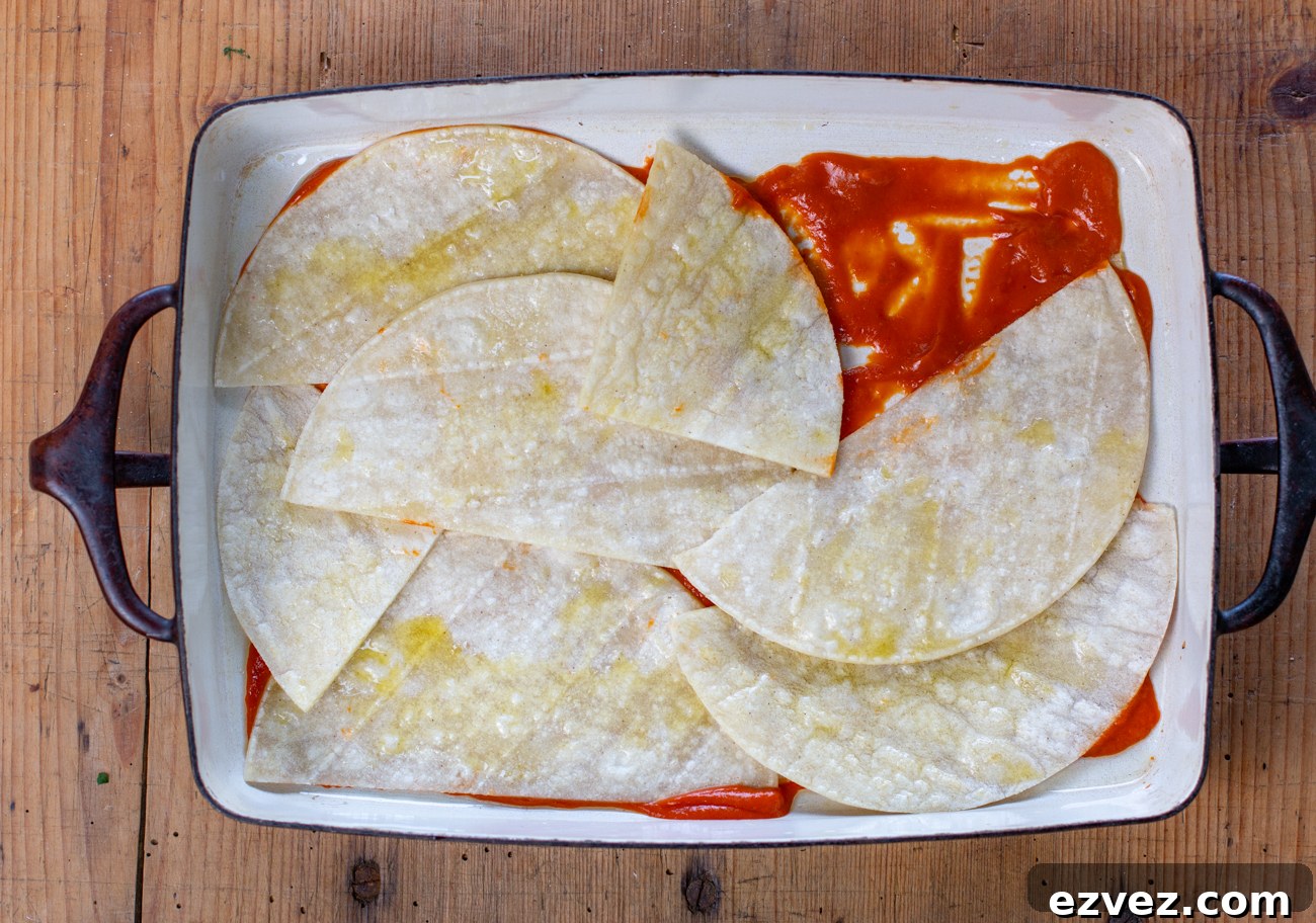 Spread sauce on the bottom of the pan and top with cut tortillas to fit
