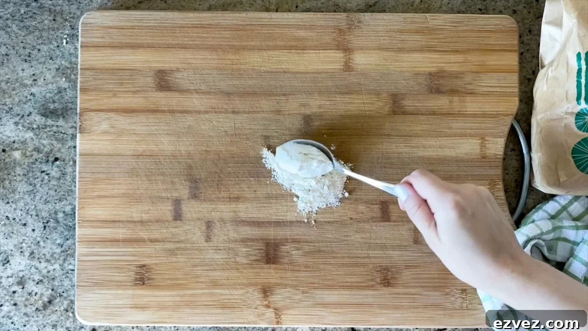 adding flour to cutting board for stretching pizza dough