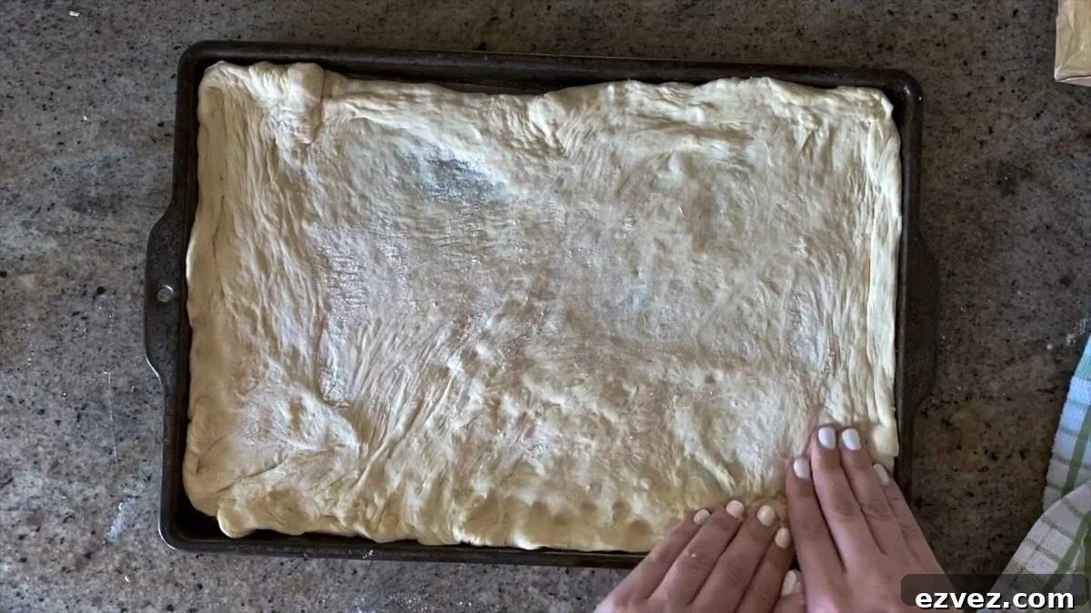 adding raw dough to a rectangle pizza tray