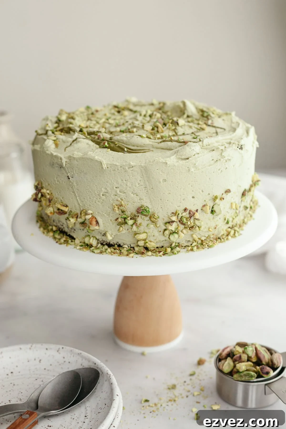 A pistachio frosted cake on a cake stand.