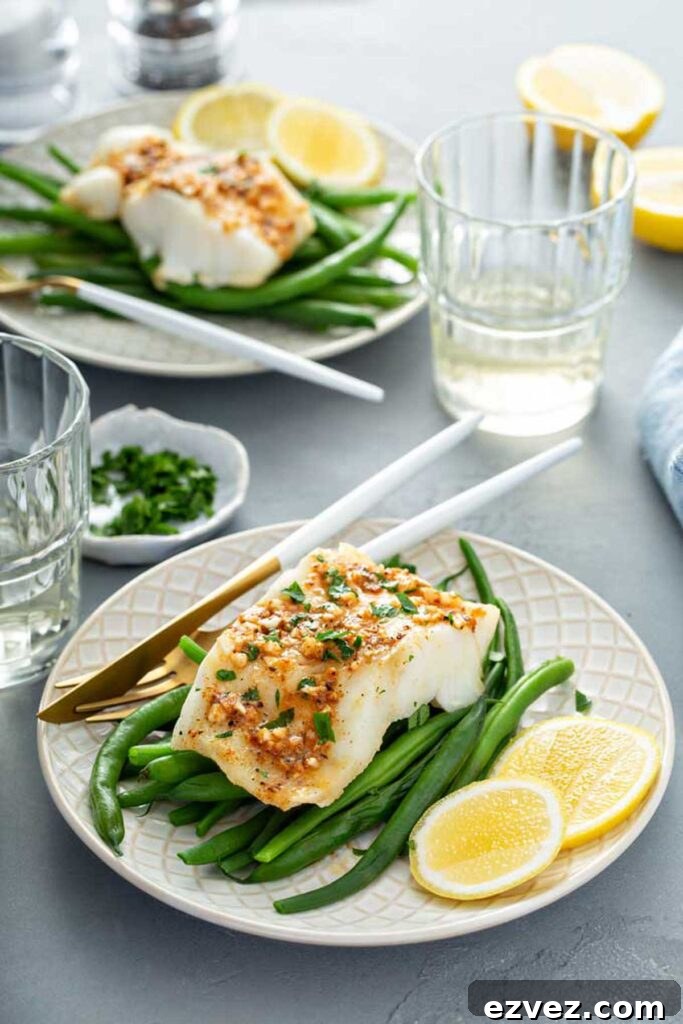 Plates served with easy baked fish fillets with cajun butter and green beans