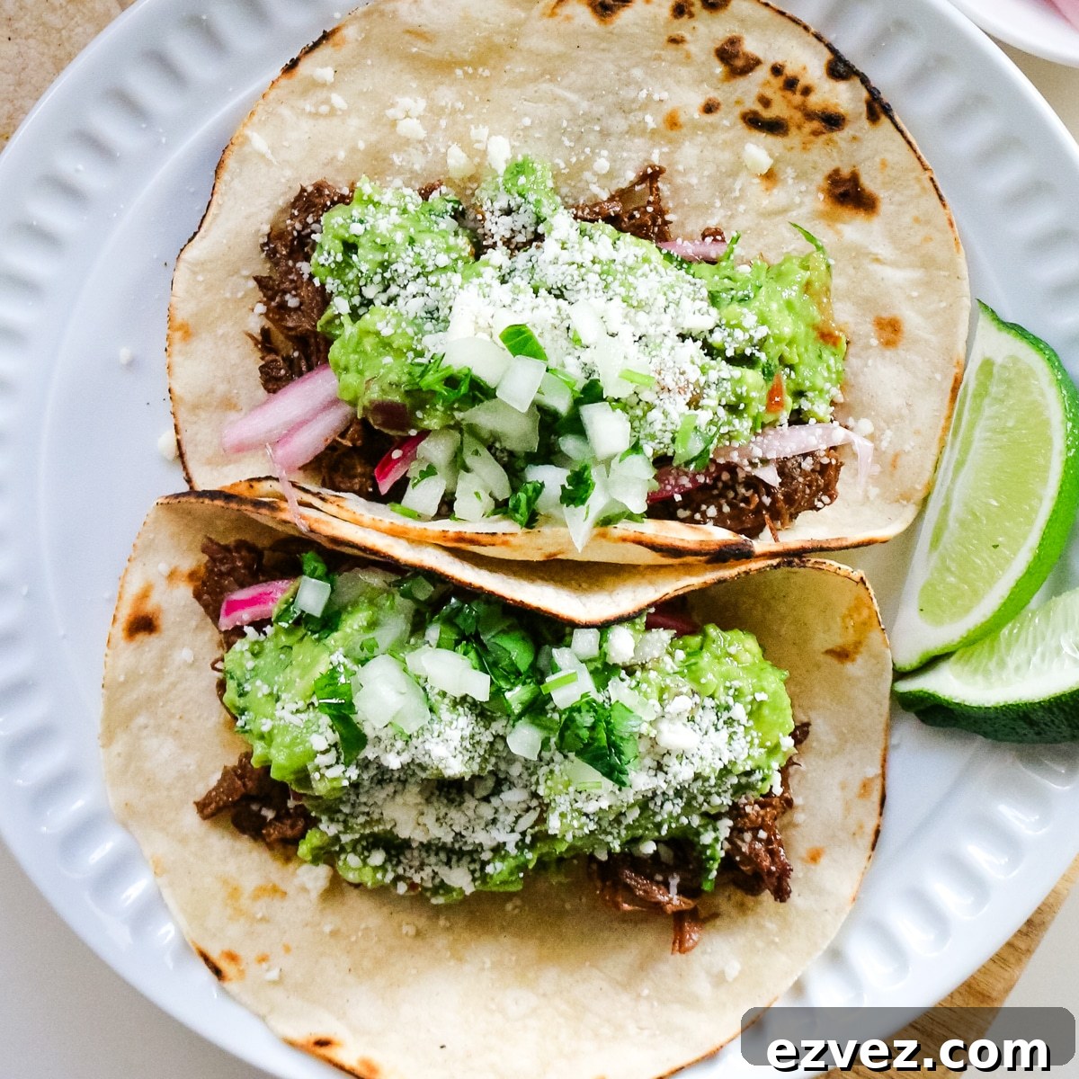 Slow-Cooker Shredded Beef Tacos for Flavorful Weeknight Meals 7 Roast tacos on a white plate with lime slices.