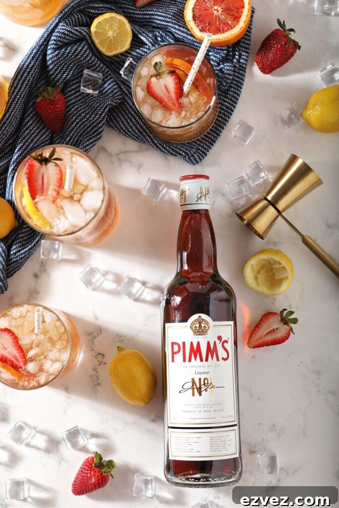 Pimm’s Punch Recipe: Classic Summer Cocktail Guide 5 Five fruity drinks garnished with strawberry sit next to a bottle of Pimm's No. 1 on marble