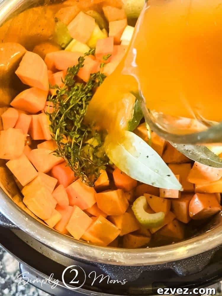 Instant pot filled with chopped butternut squash, onions, celery, and fresh herbs with vegetable broth