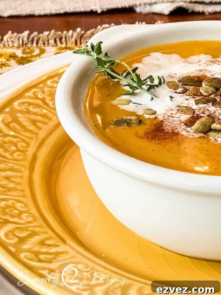 Bowl of vegan autumn squash soup garnished with coconut milk and pumpkin seeds on a plate