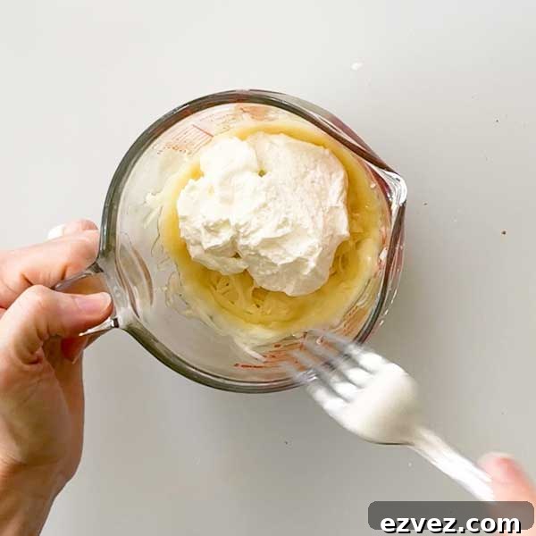 Adding the breadstick ingredients to a microwave-safe bowl and mixing with a fork.