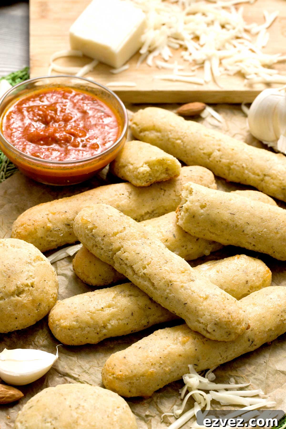 A stack of gluten-free copycat Olive Garden breadsticks next to a bowl of marinara sauce.