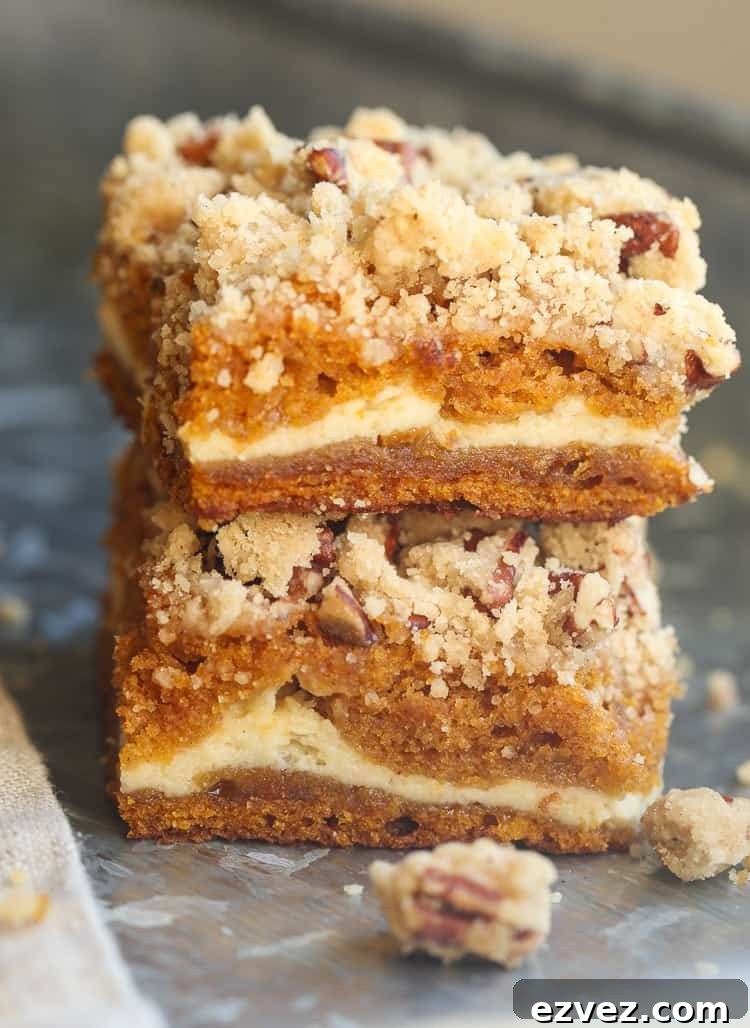 Two pumpkin cheesecake bars topped with praline stacked on top of one another.