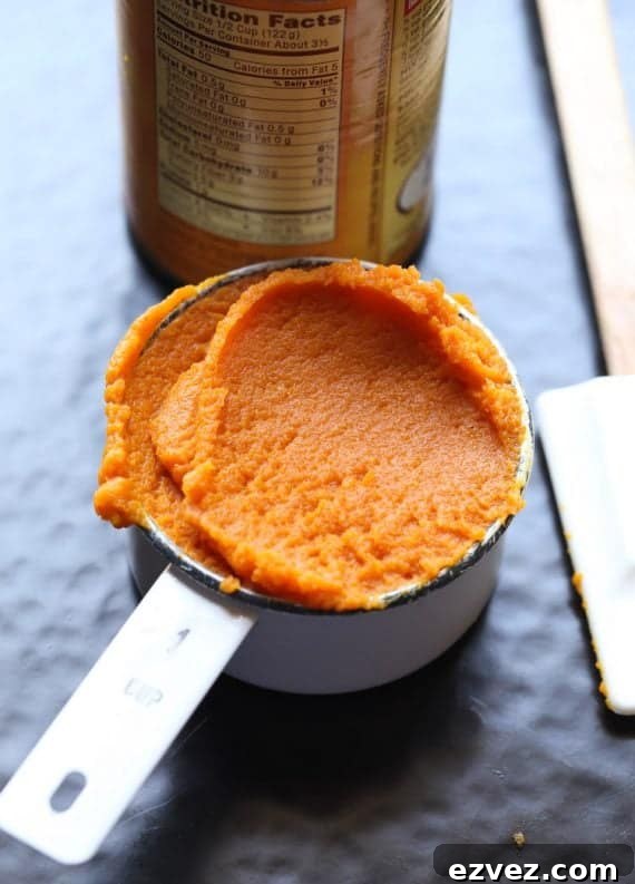 A measuring cup full of pumpkin puree next to a can of it.