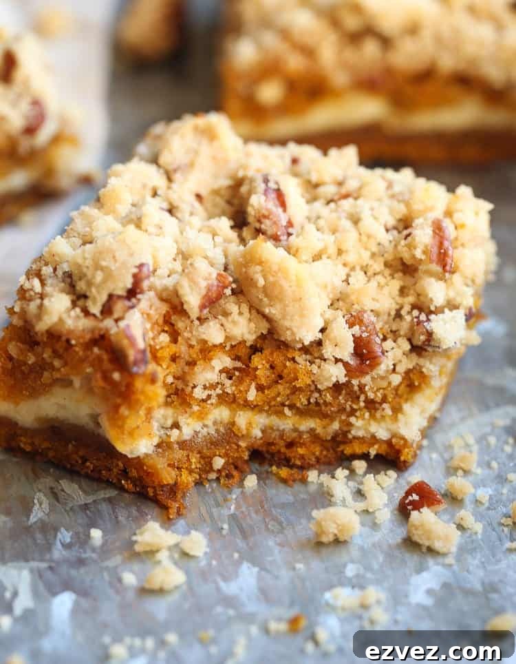 A pumpkin cheesecake bar topped with praline with a bite missing.