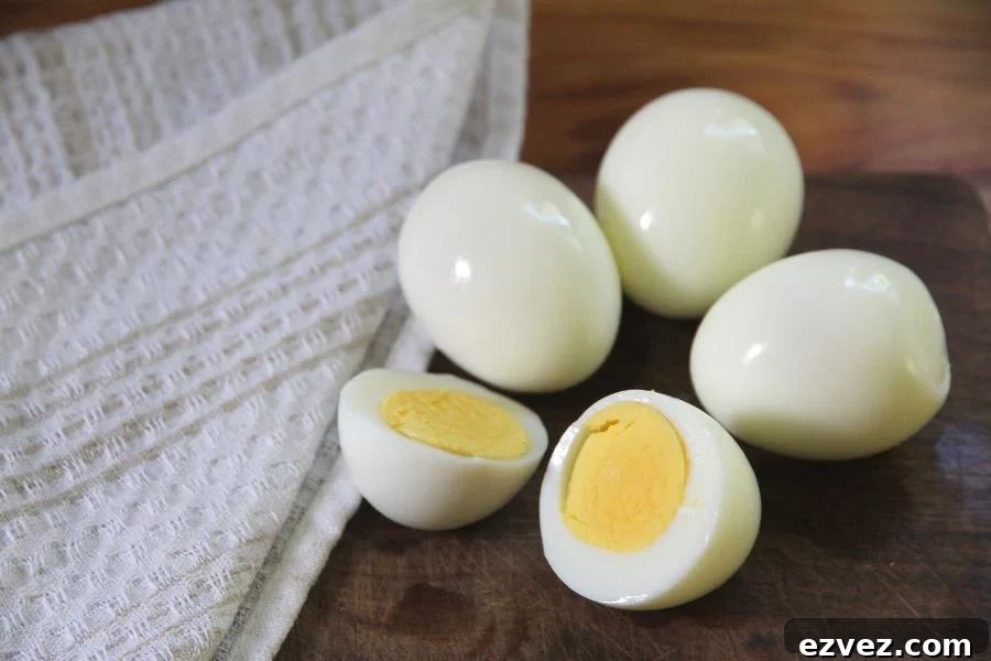 Four freshly peeled hard boiled eggs sitting on a wooden cutting board