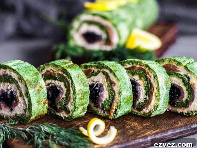 11 Party Appetizers Guests Devour Immediately 3 Sliced spinach roll with cream cheese, smoked salmon, and black caviar filling, arranged on a wooden board with dill and lemon garnishes.