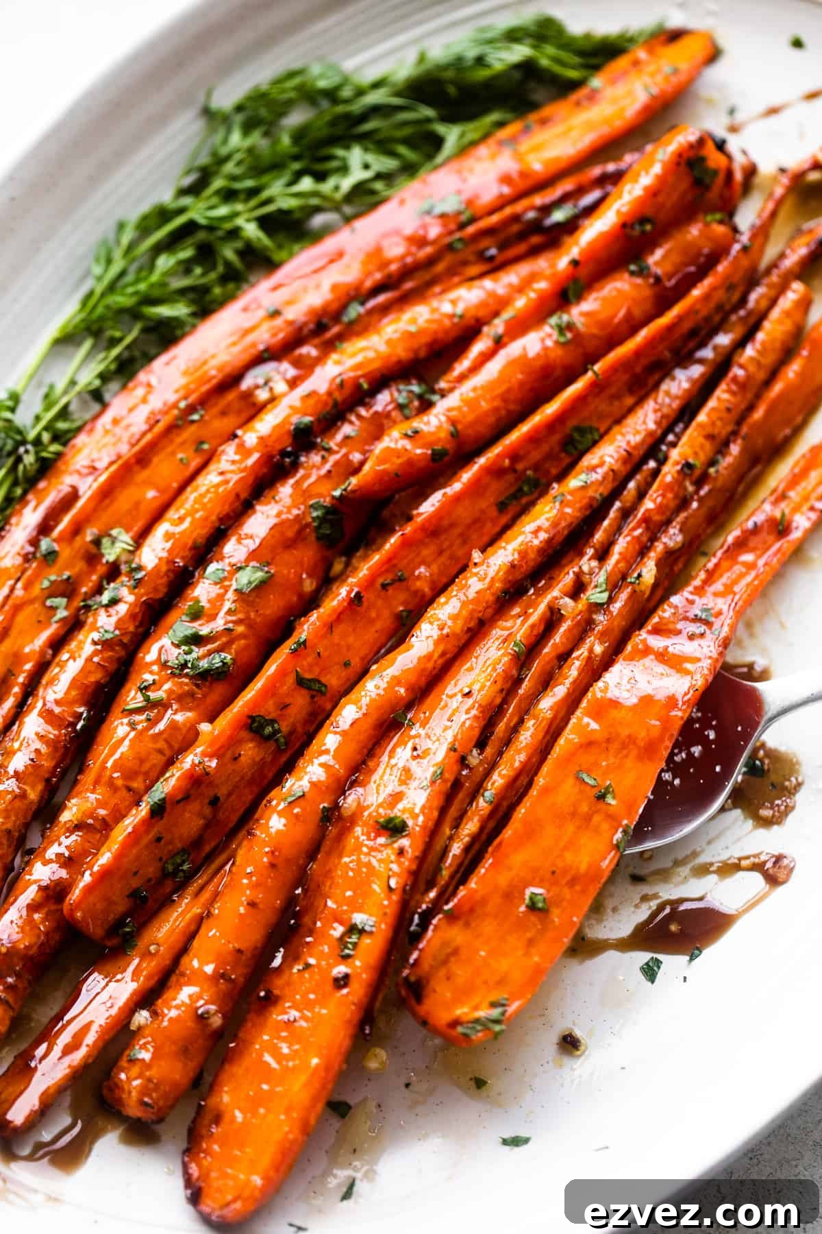 Close-up side shot of carrots arranged on a long oblong platter and drizzled with balsamic glaze.