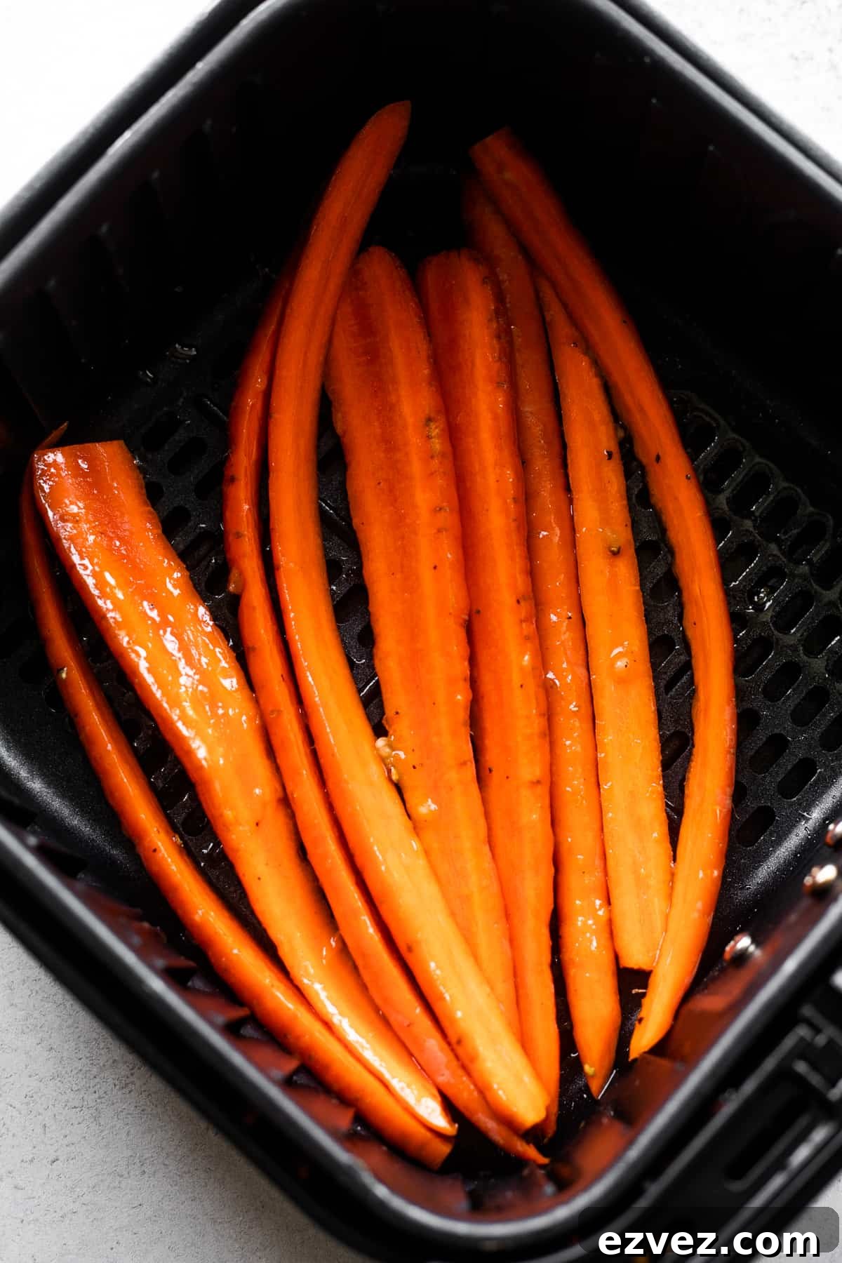 Long carrots in a black air fryer basket.