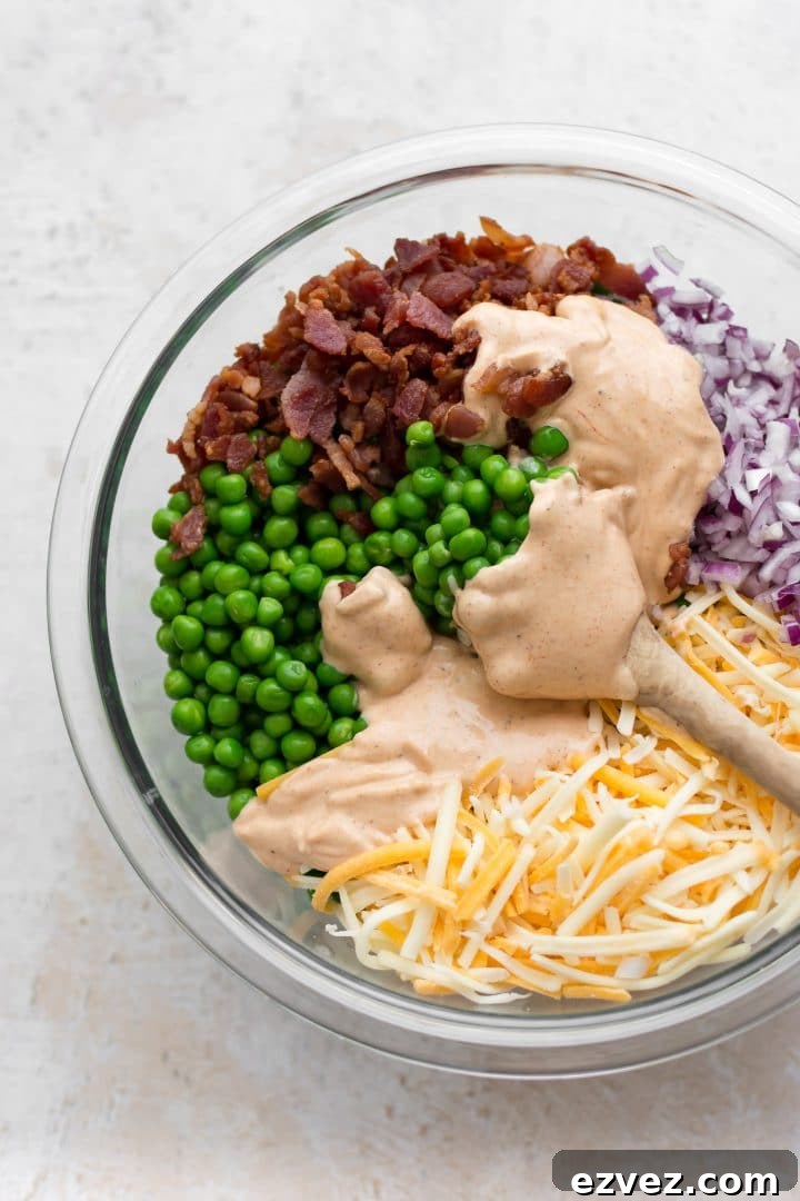 Creamy pea salad ingredients in a mixing bowl