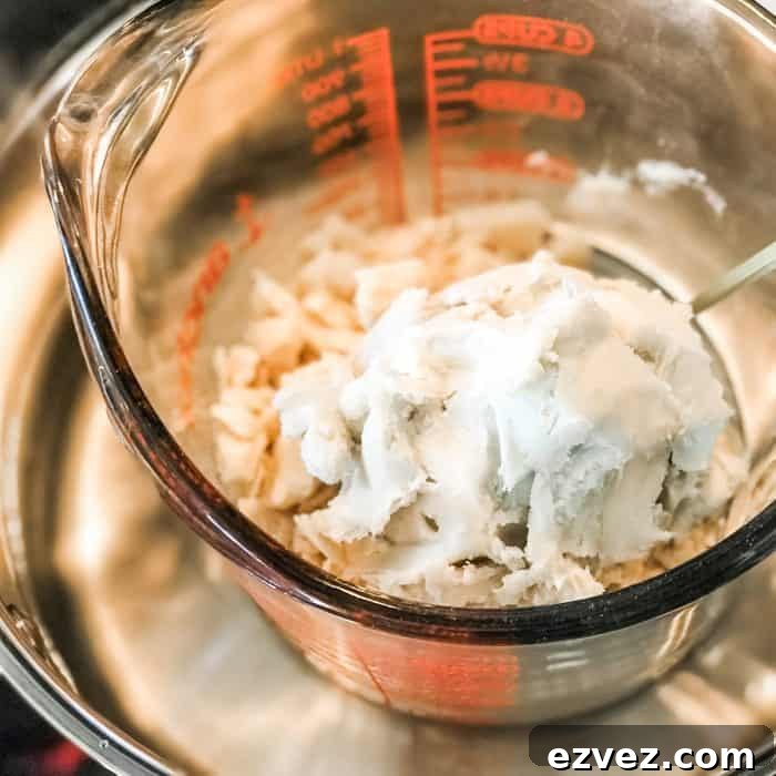 cocoa butter and shea butter in glass jar on top of saucepan with water, melting for use in Lush Buffy Bar
