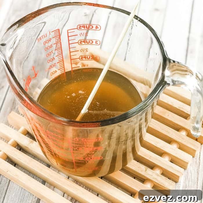 melted cocoa butter and shea butter in glass measuring cup, simmering after melting for use in DIY Lush Buffy Bar with essential oils