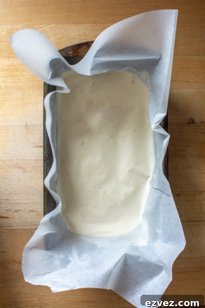 The ice cream in a loaf pan with a piece of parchment paper on top