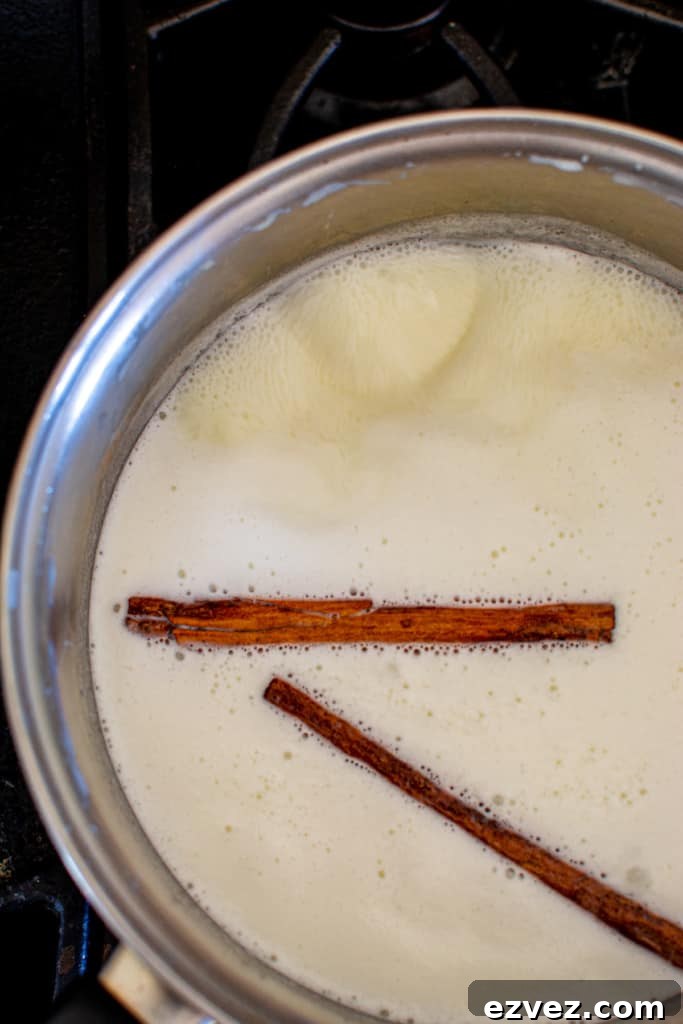 A saucepan with simmering milk and cinnamon sticks