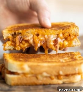 hand lifting up half of a sandwich with cheese and beans dripping out