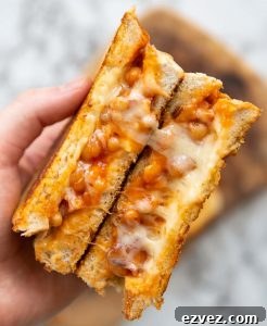 overhead shot of open sandwich showing cheesy beans above marble background
