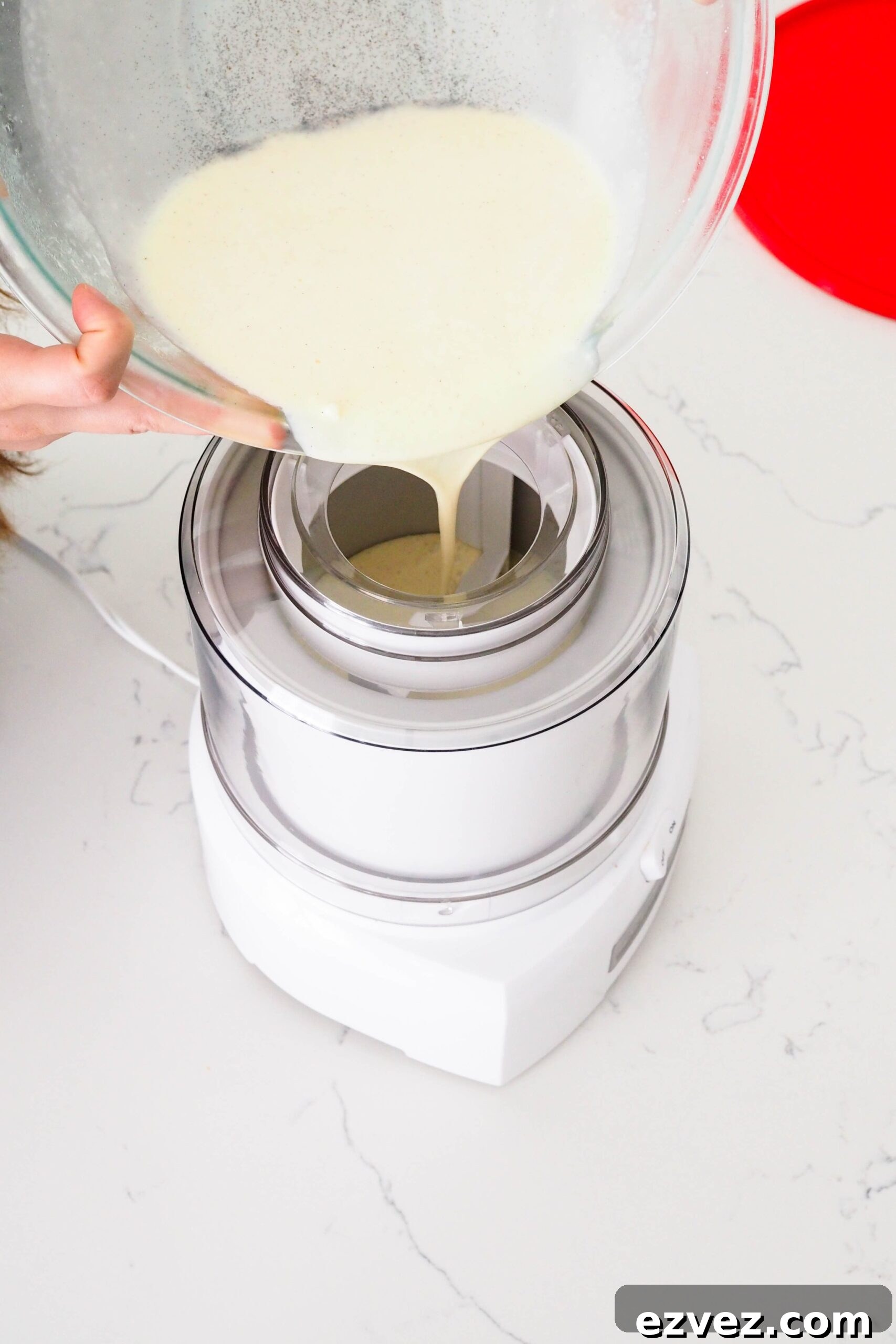 Two hands pour French vanilla ice cream base into an ice cream maker.