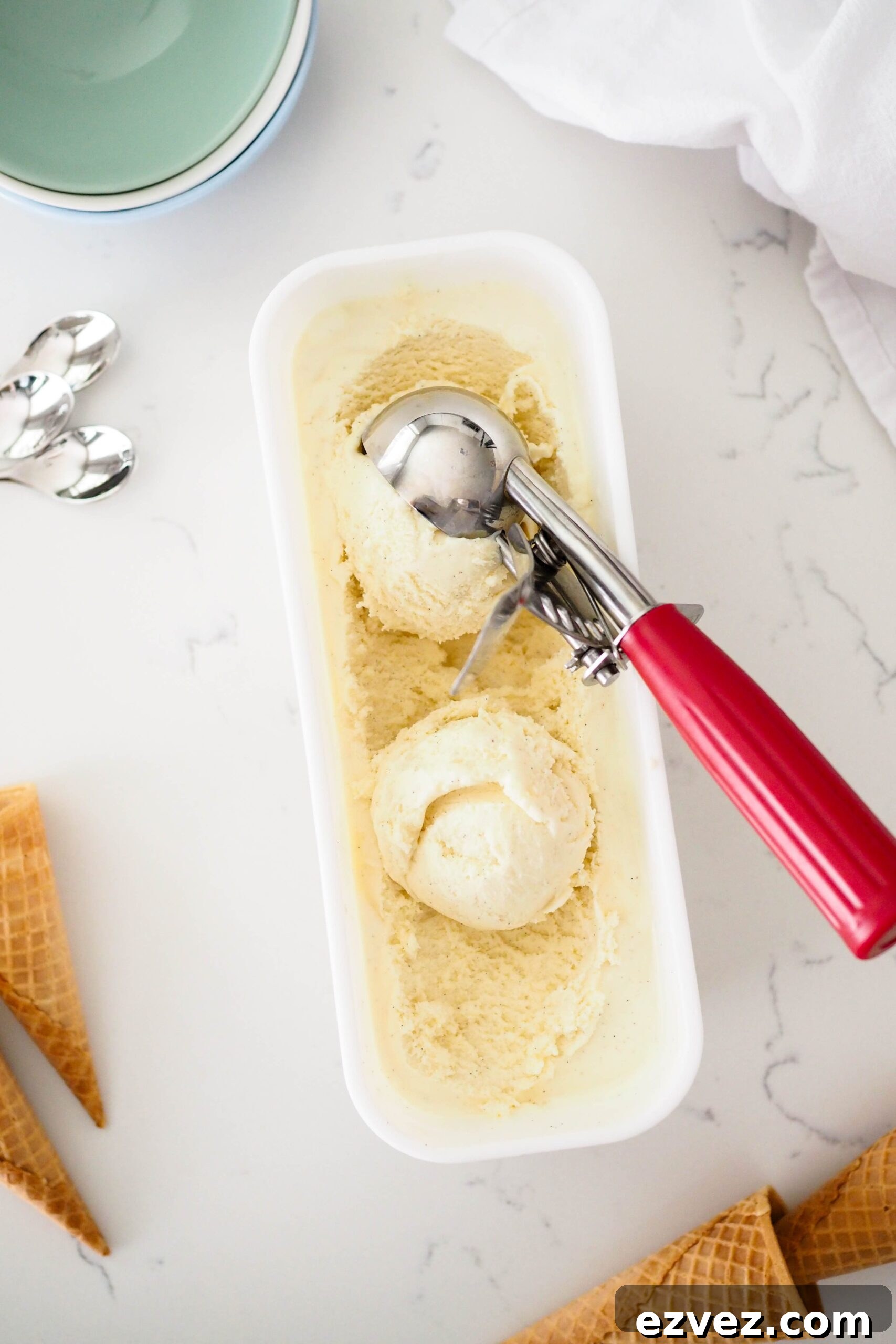 An overhead view of an ice cream scoop getting a scoop of French vanilla ice cream.