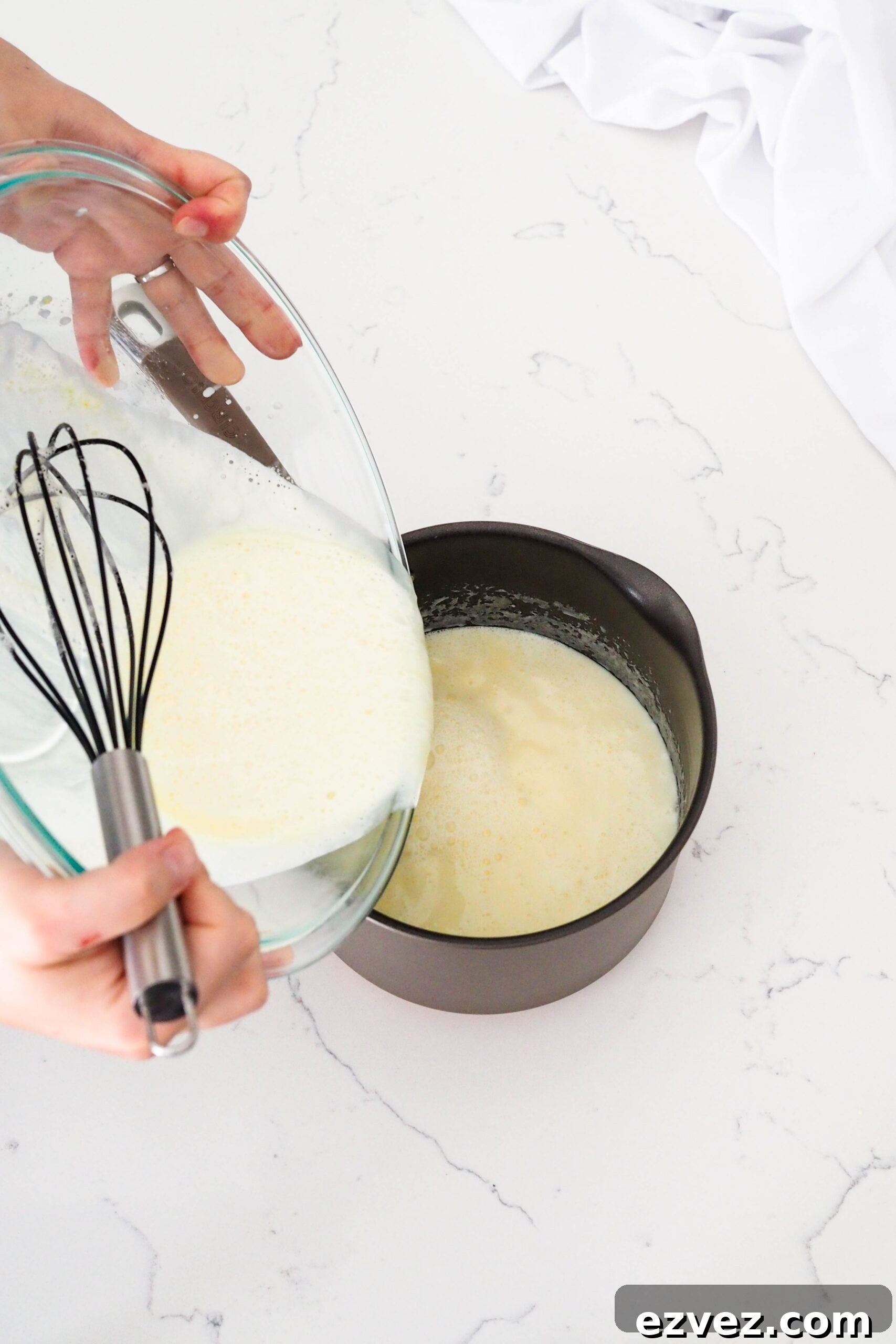 Two hands pour fresh custard back into a pot.
