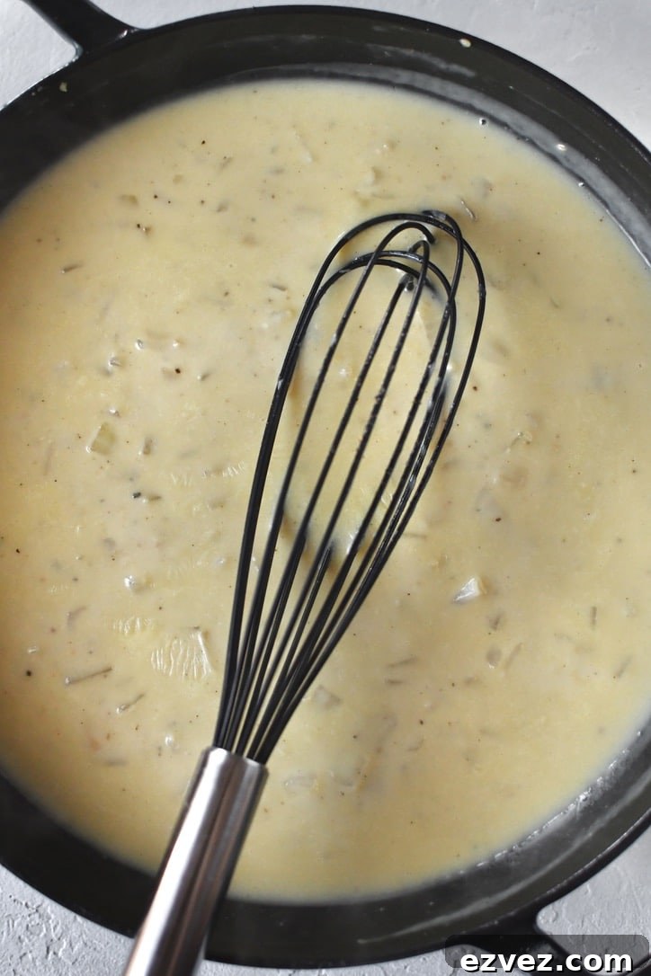 Chicken stock being whisked in and forming a sauce.