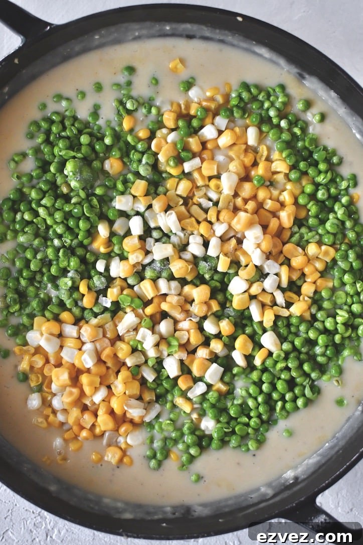 Adding the peas and corn to the sauce.