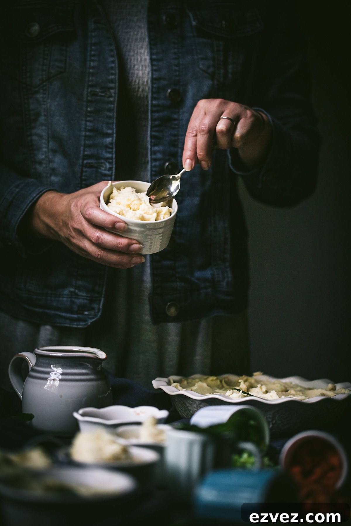 girl in denim jacket smooths mashed potatoes on top of cottage pie