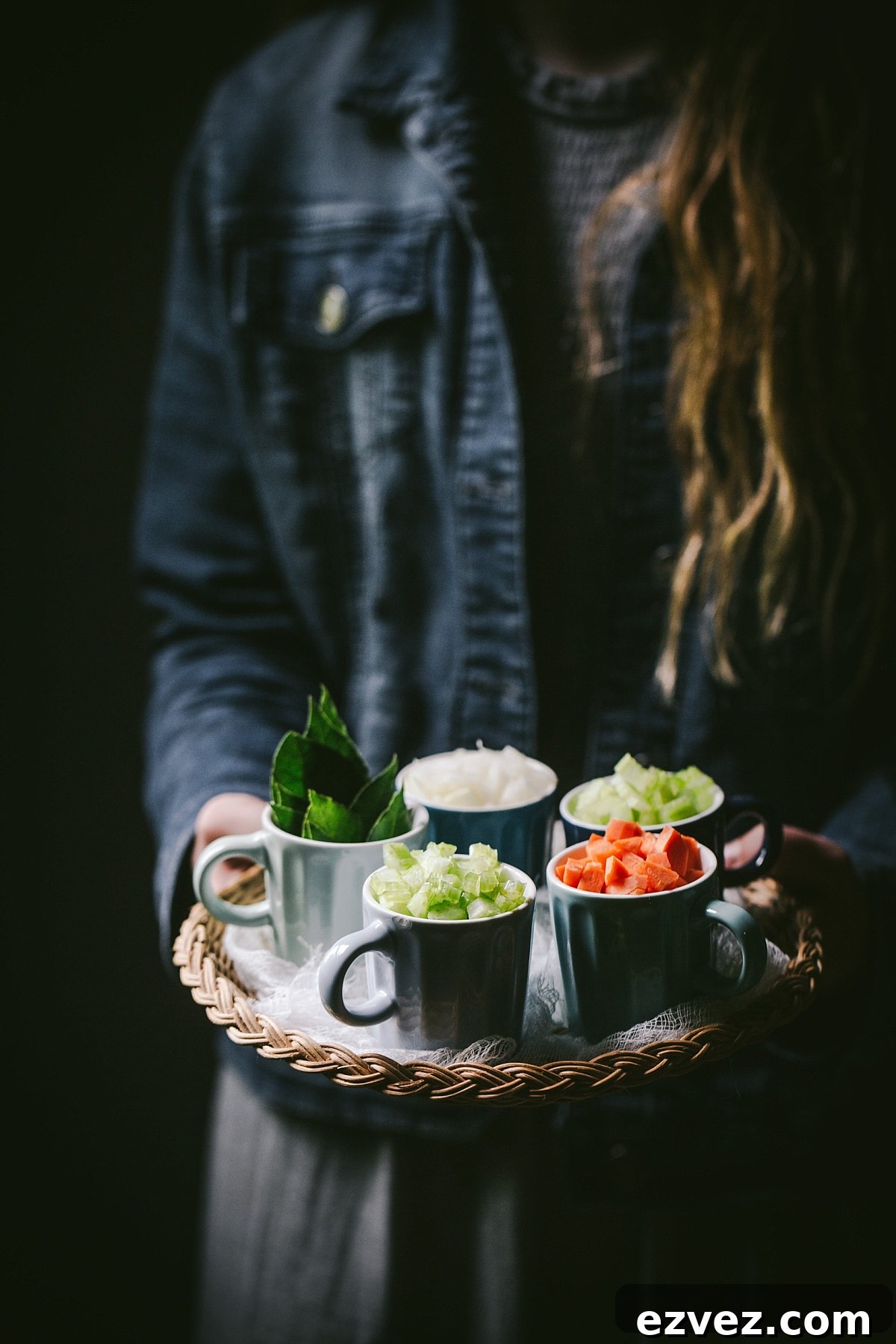girl holds tray of carrots, celery, onion, and bay leaves for guinness shepherds pie