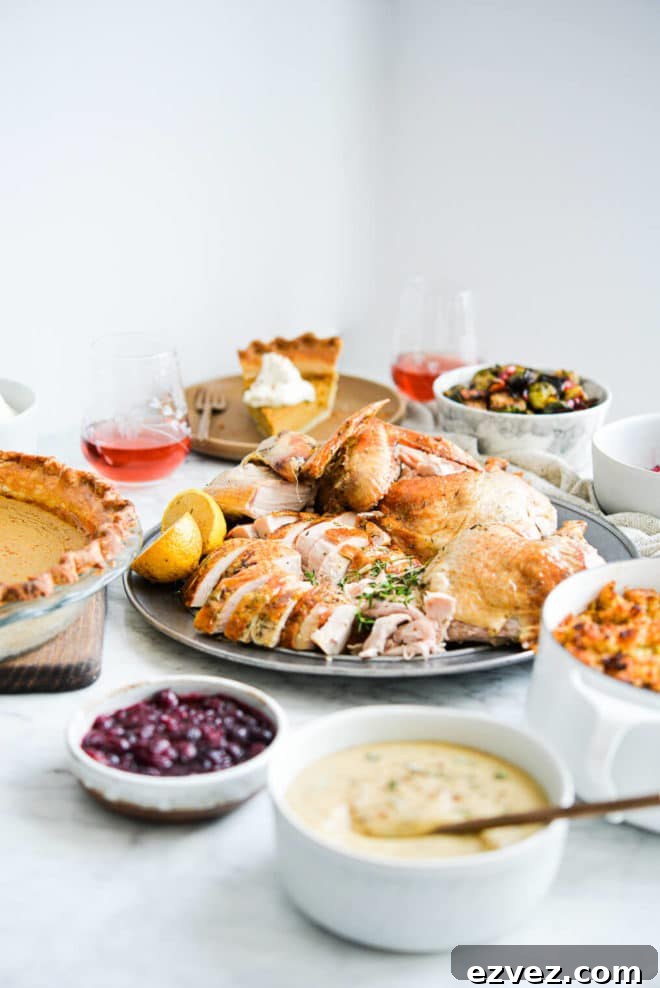 side view of a thanksgiving holiday spread complete with pumpkin pie, carved whole turkey, classic gravy, wine, cranberry sauce, brussels sprouts, and semi-homemade stuffing