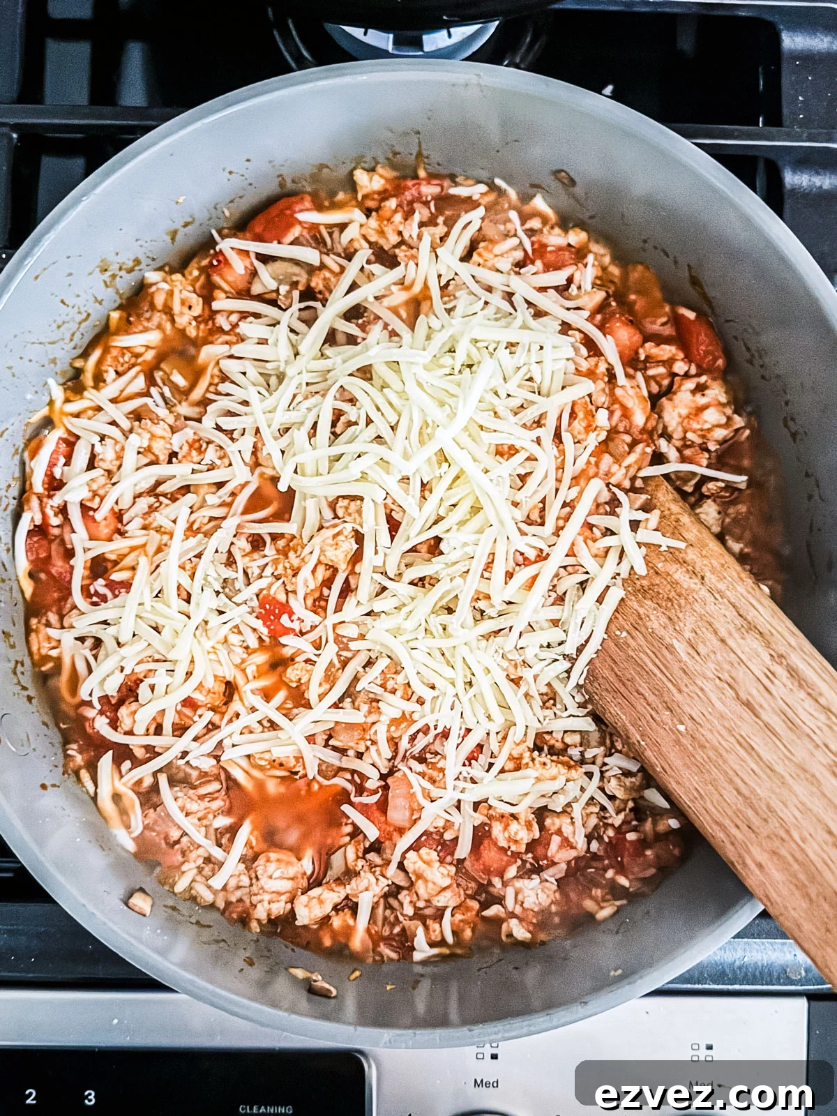 Turkey-Stuffed Bell Peppers with Savory Rice Filling 7 Saucy ground turkey sprinkled with cheese in a skillet.