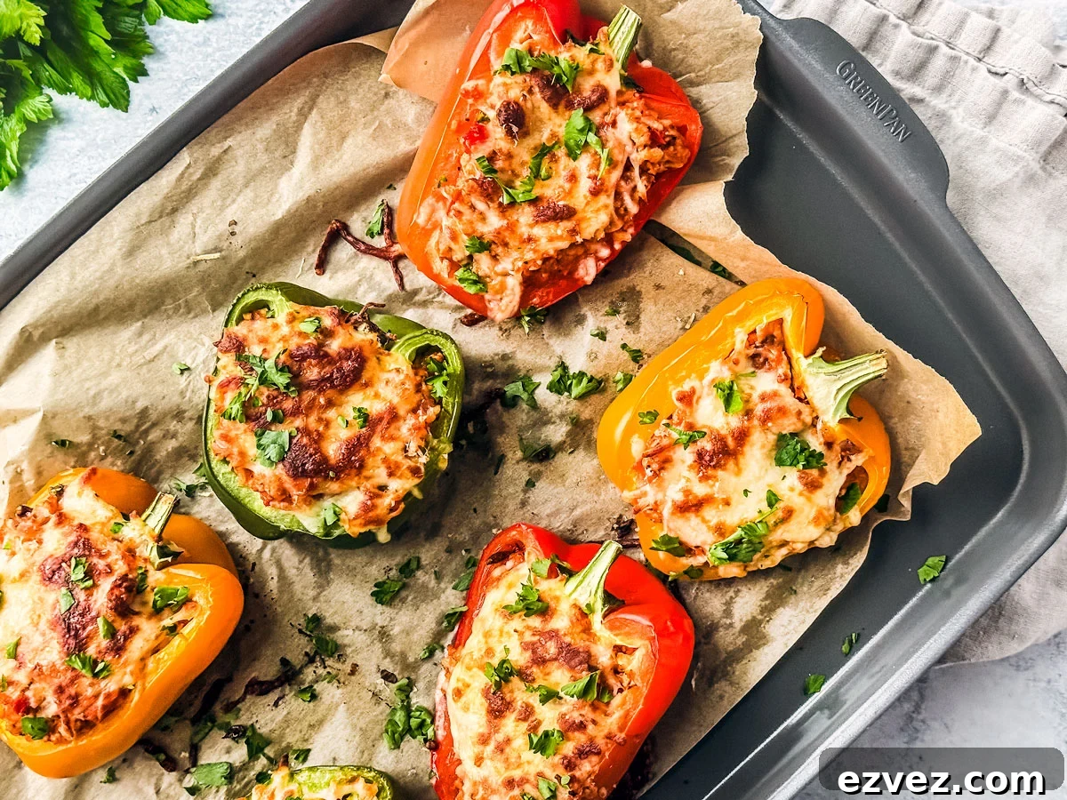 Turkey-Stuffed Bell Peppers with Savory Rice Filling 10 Baked stuffed peppers with ground turkey on a baking sheet with parchment paper.
