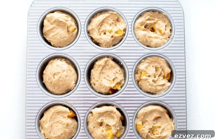 cake batter and peaches in muffin tin
