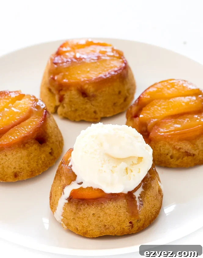 Mini Peach Upside Down Cakes on a white plate with a scoop of ice cream.
