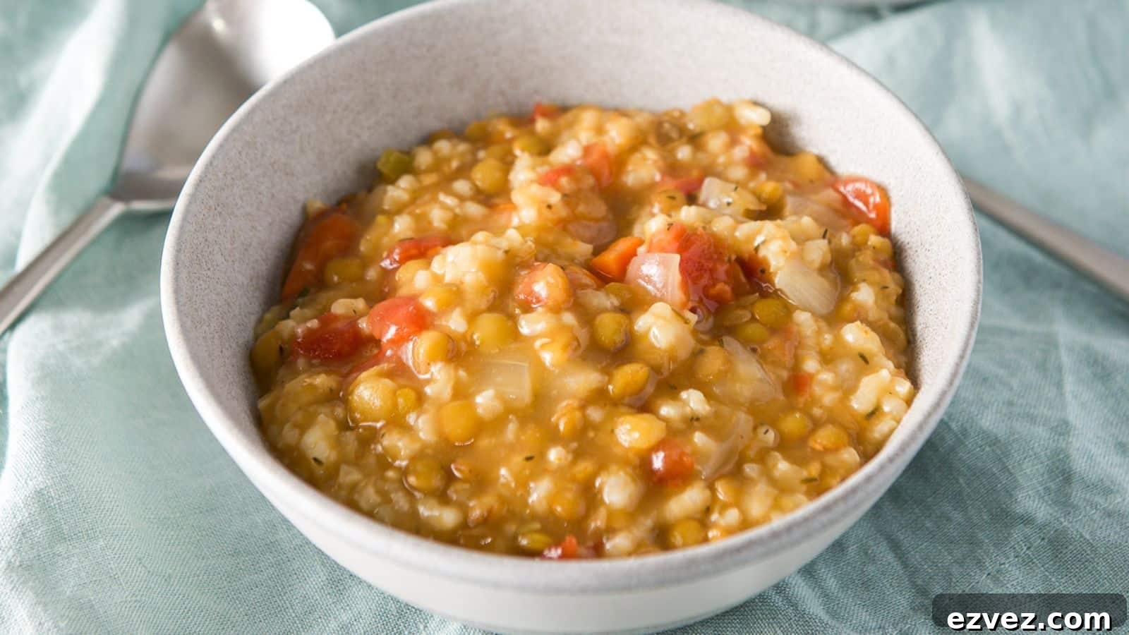 a grey bowl filled with lentil and rice soup on a green napkin