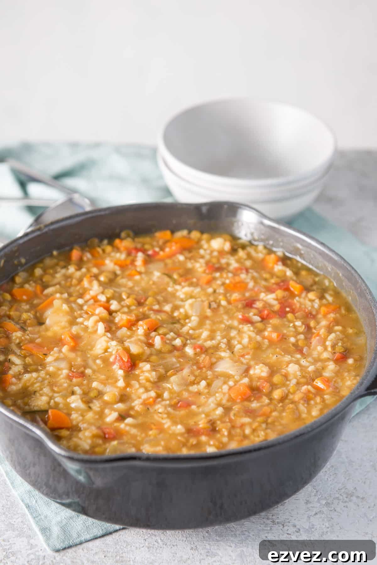 A big dark grey cast iron pan filled with the instant pot soup with two grey bowls in the background